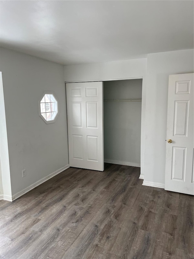 unfurnished bedroom with dark wood-type flooring, baseboards, and a closet