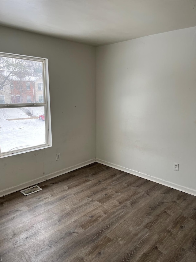 unfurnished room with visible vents, dark wood-style flooring, and baseboards