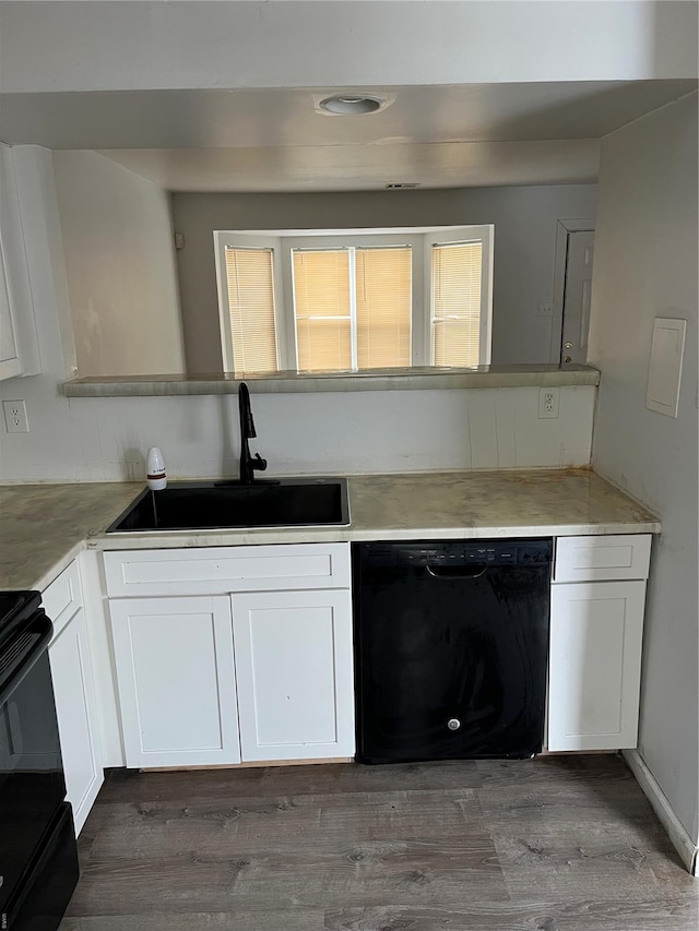 kitchen featuring stove, a sink, white cabinets, black dishwasher, and dark wood-type flooring
