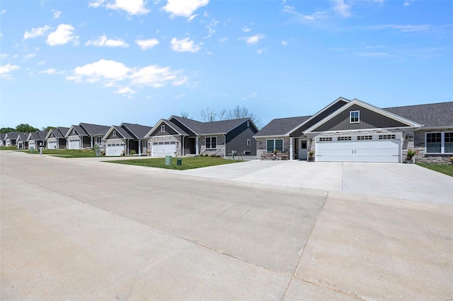 view of front of house with an attached garage, a residential view, driveway, and stone siding