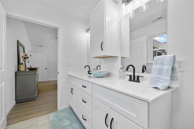 bathroom with a sink, baseboards, double vanity, and visible vents