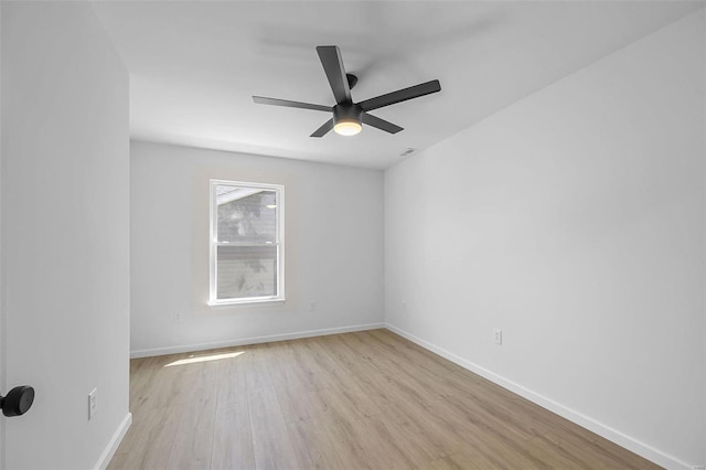 spare room featuring ceiling fan, baseboards, and light wood-type flooring