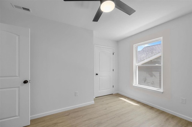 spare room featuring a ceiling fan, baseboards, visible vents, and light wood finished floors