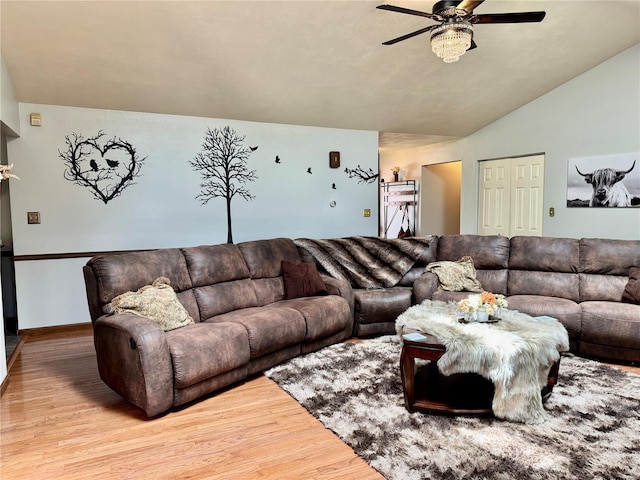 living area featuring baseboards, ceiling fan, vaulted ceiling, and wood finished floors