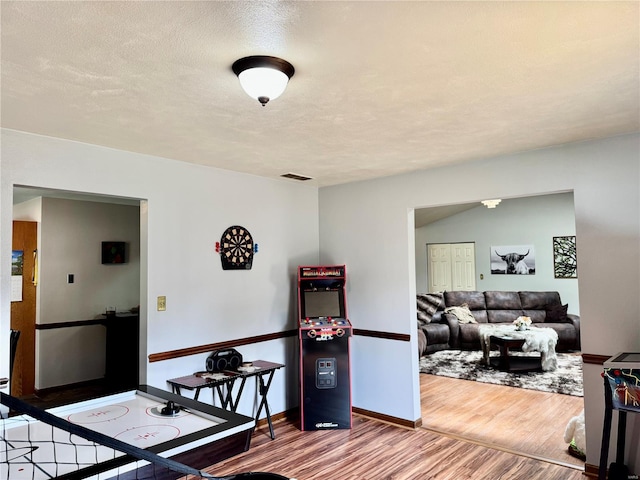 dining room featuring a textured ceiling, baseboards, visible vents, and wood finished floors