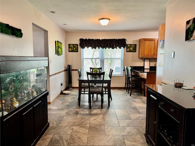 dining room with baseboards and stone finish flooring