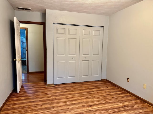 unfurnished bedroom with light wood-type flooring, baseboards, and a closet