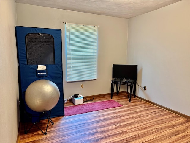 exercise room featuring baseboards, a textured ceiling, and wood finished floors