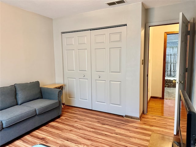 living room featuring light wood-style floors, baseboards, and visible vents