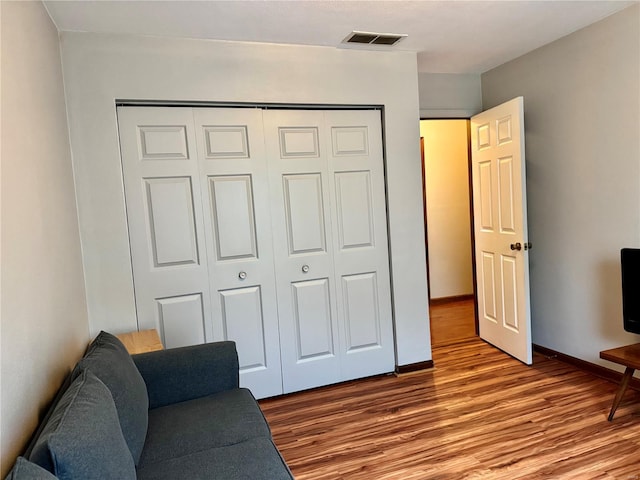 living area featuring baseboards, wood finished floors, and visible vents
