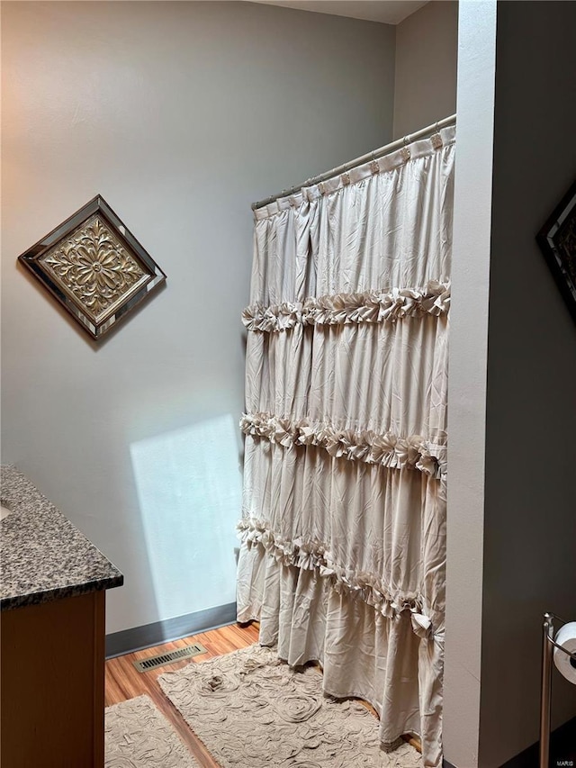 bathroom featuring vanity, a shower with shower curtain, wood finished floors, and visible vents