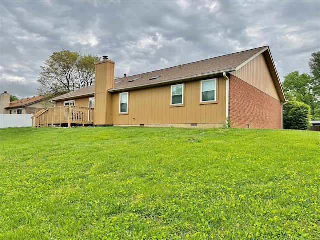 rear view of house with a wooden deck, a chimney, a shingled roof, crawl space, and a yard