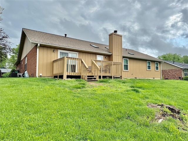 back of property with a lawn, a deck, a chimney, and roof with shingles