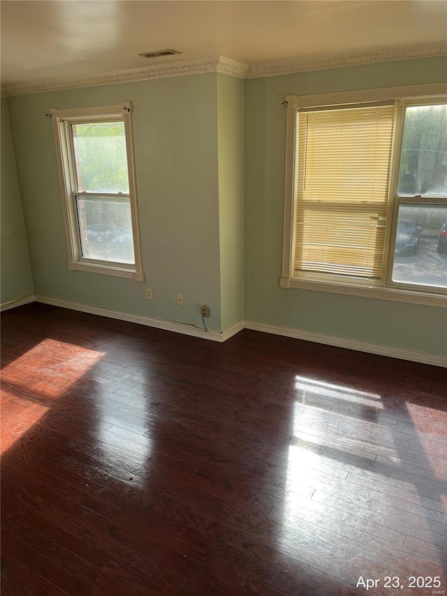 unfurnished room featuring visible vents, baseboards, crown molding, and hardwood / wood-style flooring