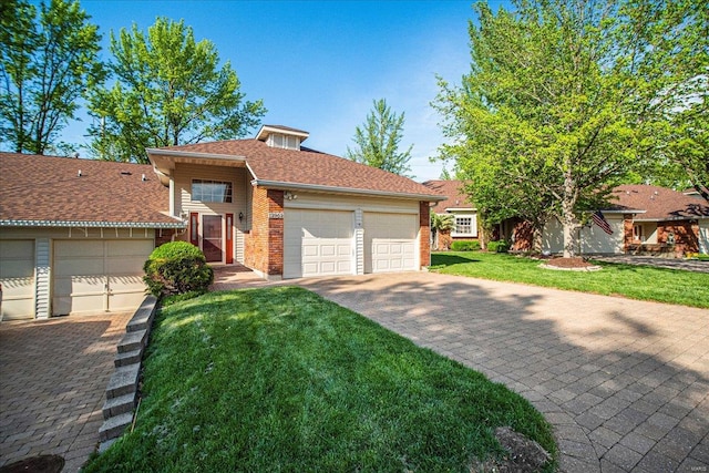 view of front facade with brick siding, a shingled roof, an attached garage, and a front yard