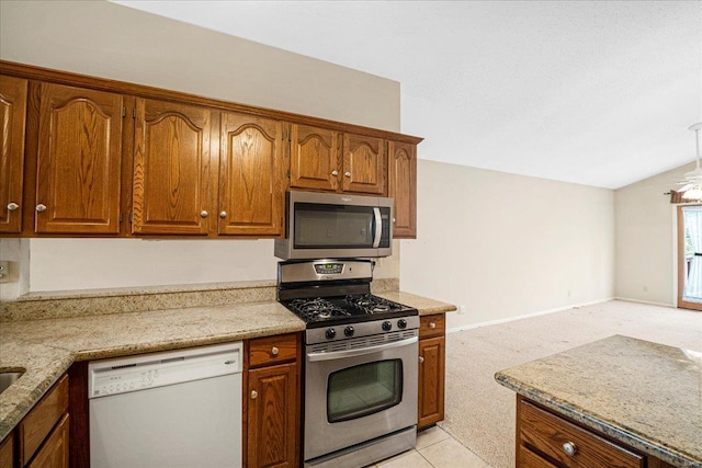 kitchen with appliances with stainless steel finishes, brown cabinetry, light stone counters, and light carpet
