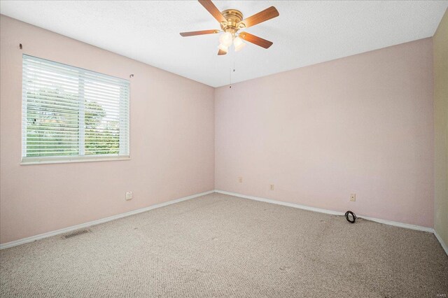 spare room with carpet flooring, ceiling fan, visible vents, and baseboards
