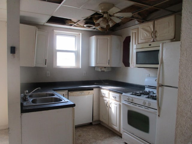 kitchen with a sink, dark countertops, a ceiling fan, and white appliances