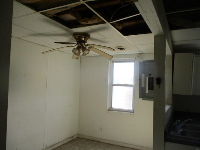 unfurnished room with ceiling fan, electric panel, visible vents, a paneled ceiling, and a sink