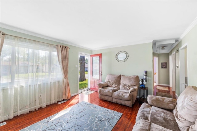 living area with crown molding, a wall mounted air conditioner, wood finished floors, and visible vents