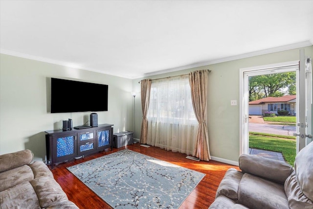 living area with baseboards, visible vents, ornamental molding, and wood finished floors