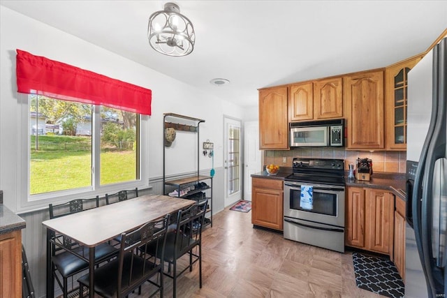 kitchen featuring dark countertops, appliances with stainless steel finishes, tasteful backsplash, and brown cabinetry