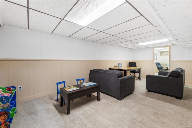 carpeted living area featuring a paneled ceiling and wainscoting
