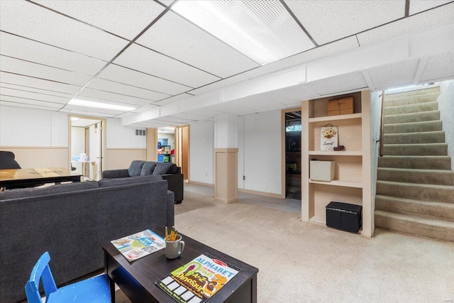 living room with carpet flooring, a drop ceiling, and stairway
