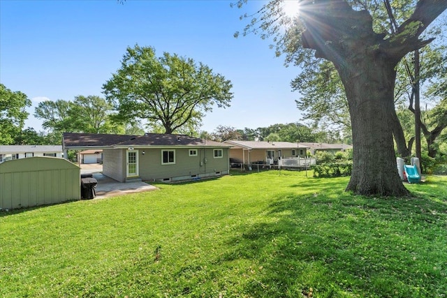 back of house featuring fence, a storage unit, a patio area, a lawn, and an outdoor structure