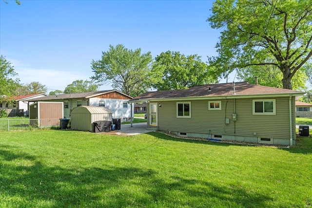 back of house with a lawn, fence, an outbuilding, and a storage unit