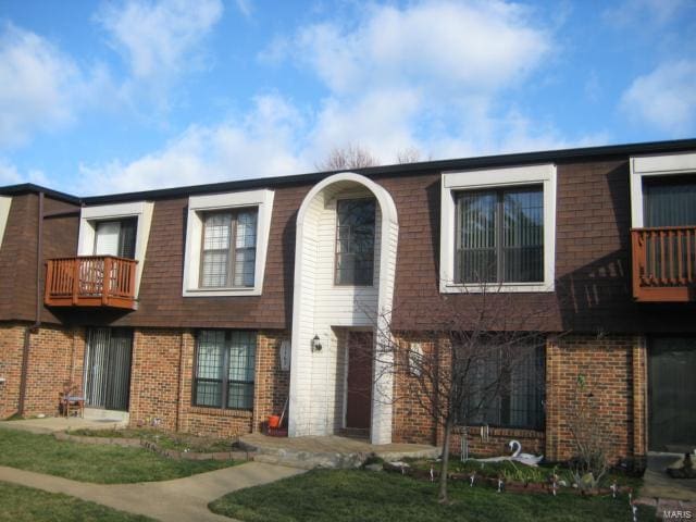 view of front of house featuring a balcony and brick siding