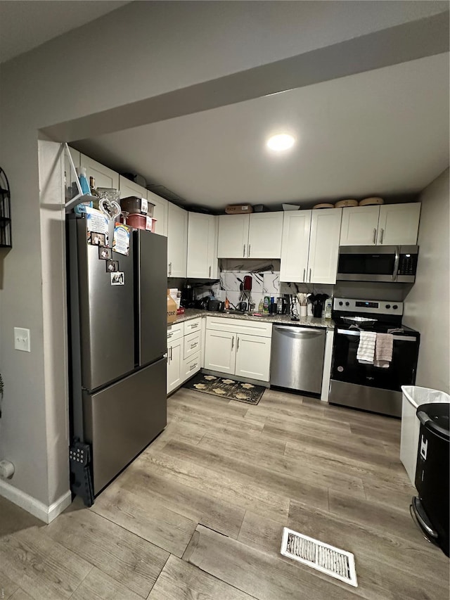 kitchen featuring visible vents, light wood-type flooring, white cabinetry, a sink, and appliances with stainless steel finishes