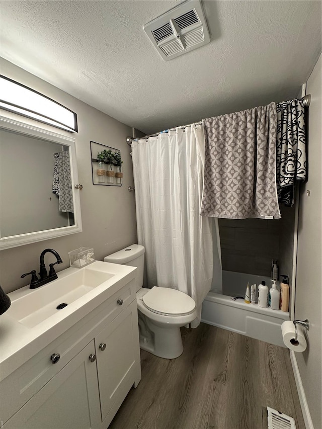 bathroom with a textured ceiling, toilet, wood finished floors, and visible vents