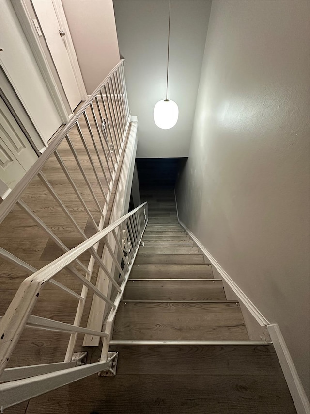 staircase with baseboards and wood finished floors