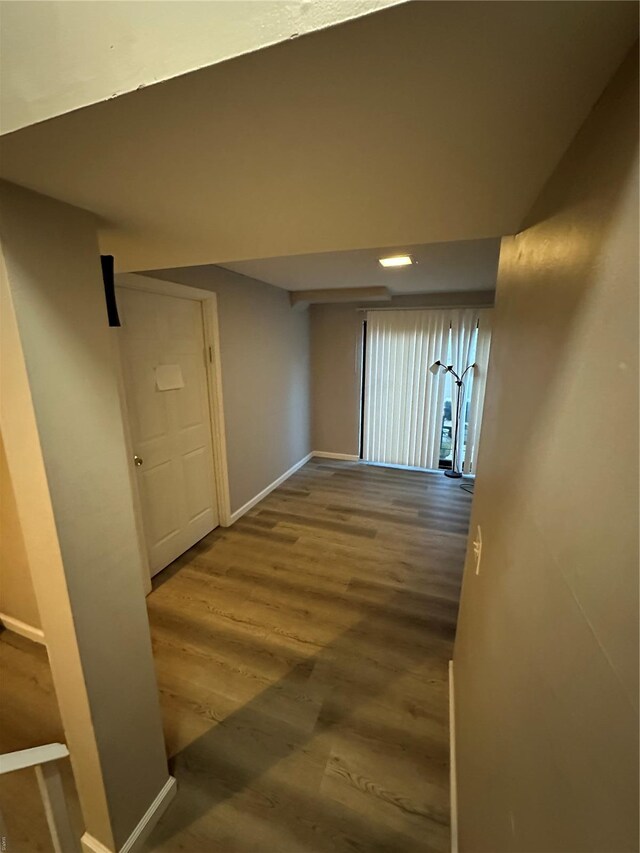 corridor featuring baseboards and wood finished floors
