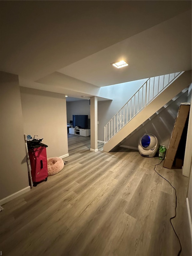 finished basement with stairway, baseboards, and wood finished floors