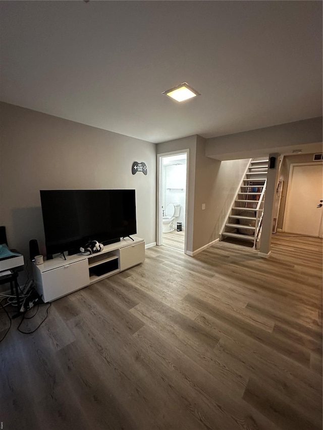 living area featuring baseboards, stairs, and wood finished floors