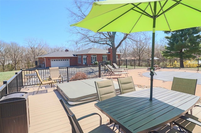 wooden terrace with an attached garage, fence, and outdoor dining space