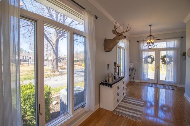 foyer with baseboards, a notable chandelier, a wealth of natural light, and hardwood / wood-style floors