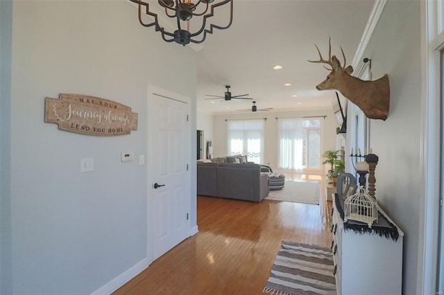 corridor with recessed lighting, ornamental molding, baseboards, and wood finished floors