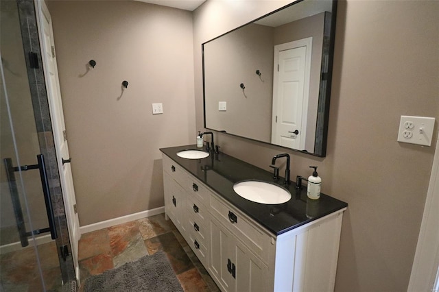 bathroom featuring a sink, baseboards, double vanity, and stone tile floors