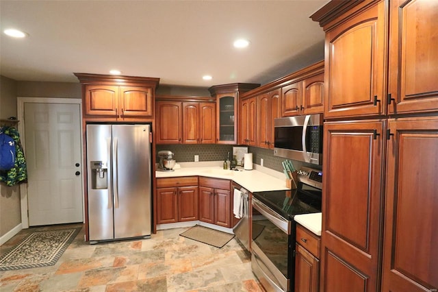 kitchen featuring brown cabinetry, recessed lighting, light countertops, appliances with stainless steel finishes, and backsplash