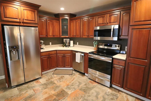 kitchen with light countertops, appliances with stainless steel finishes, stone finish floor, and glass insert cabinets