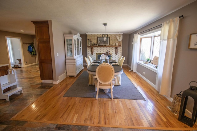 dining room with baseboards, a brick fireplace, recessed lighting, and wood finished floors