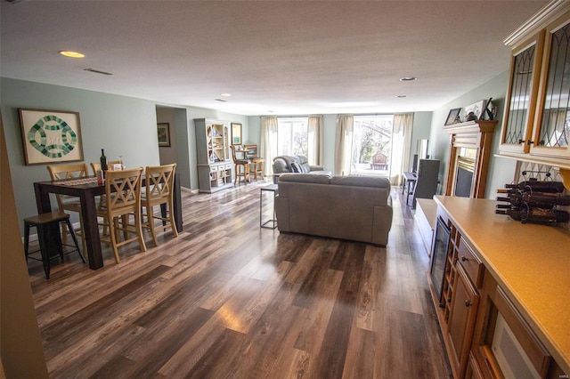 living room featuring a fireplace, recessed lighting, wine cooler, visible vents, and dark wood-type flooring