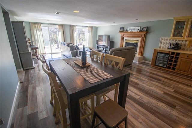 dining space featuring visible vents, dark wood-style flooring, baseboards, recessed lighting, and a tiled fireplace