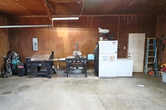 garage with freestanding refrigerator, fridge, and wood walls