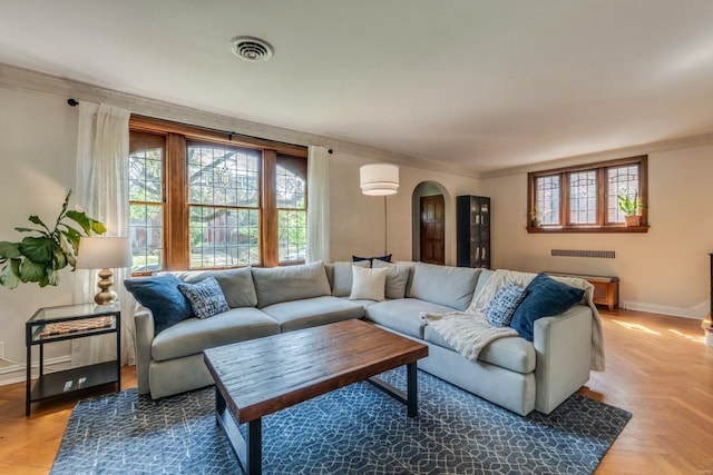 living area with arched walkways, baseboards, visible vents, and ornamental molding