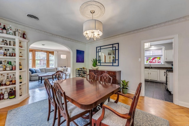 dining area with arched walkways, plenty of natural light, baseboards, and visible vents