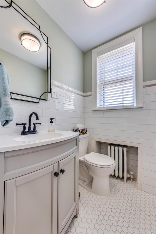 bathroom with radiator heating unit, toilet, and tile walls